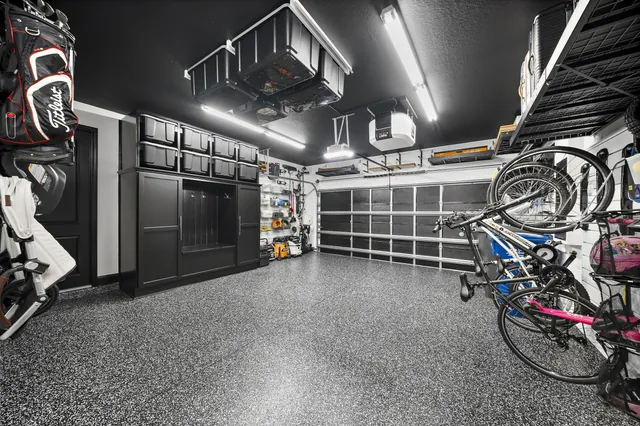 Black storage and ceiling finishes frame the white slatwall, giving a busy garage a consistent visual order.