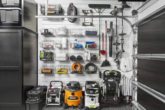 Battery-powered lawn equipment and long-handled cleaning tools hang individually, so one item can be reached without moving the rest.