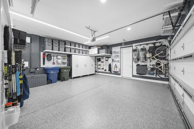 Cabinetry, slatwall, and overhead shelving give household supplies, everyday gear, and seasonal storage distinct places around the parking bay.