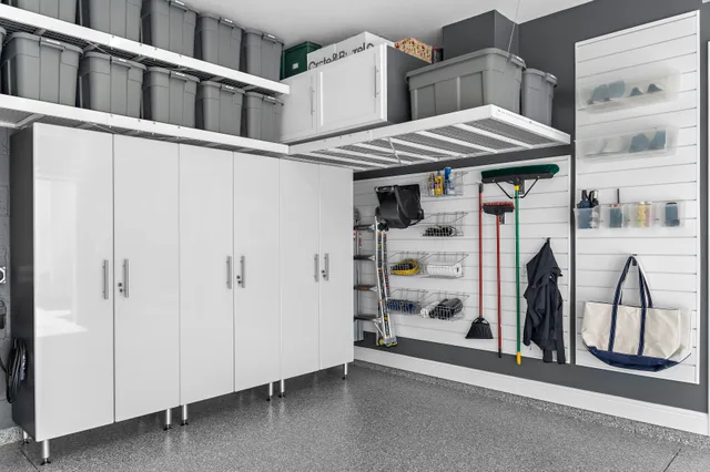 Tall white cabinets, overhead bins, and slatwall accessories give household supplies and everyday equipment distinct places.