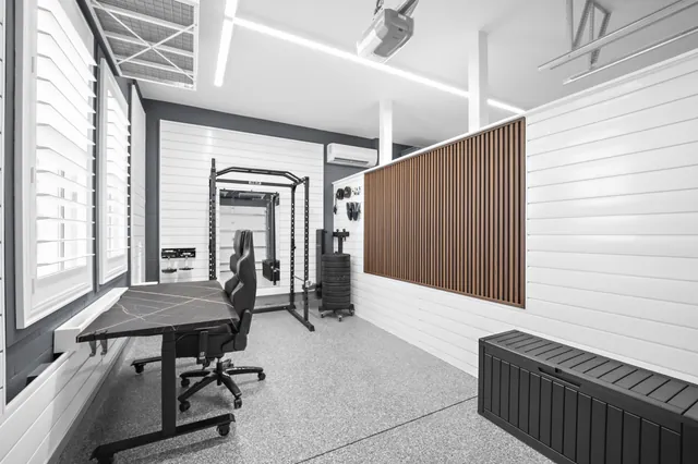A desk along the window and fitness equipment at the end of the bay allow both uses to share the space beside the partition.