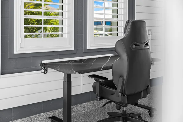The desk and chair sit beside shuttered windows in the workspace.