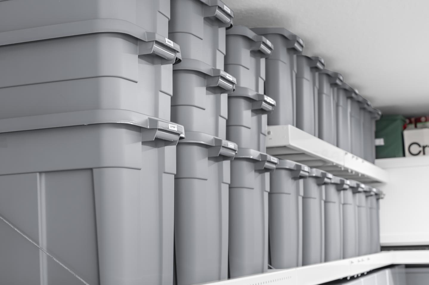 Matching labeled bins arranged on two levels of overhead shelving after organization