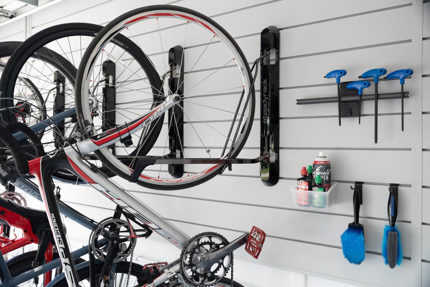 Wall-mounted bikes with riding and maintenance accessories neatly arranged on white slatwall