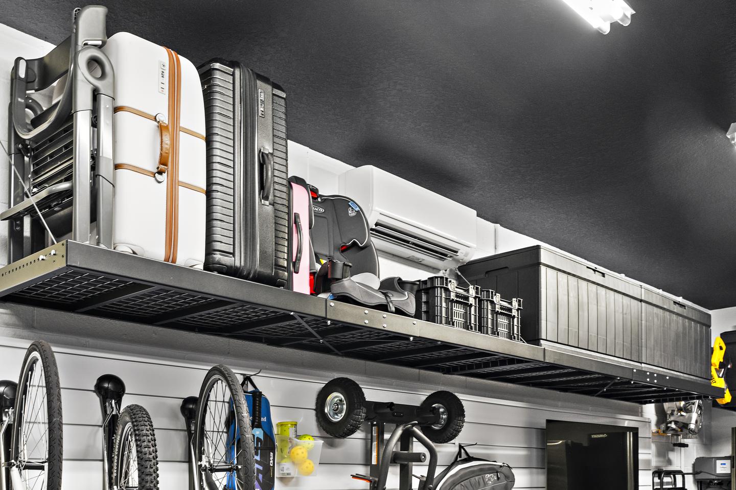 Luggage, folded furniture, and storage containers on high shelving above partially visible bikes