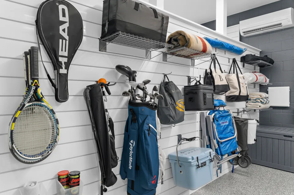 Golf bags, tennis rackets, beach chairs, and coolers arranged on the storage side of the partition.