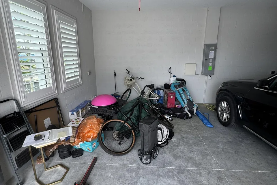 Before the work: bikes, household belongings, and a parked vehicle share the unfinished garage.