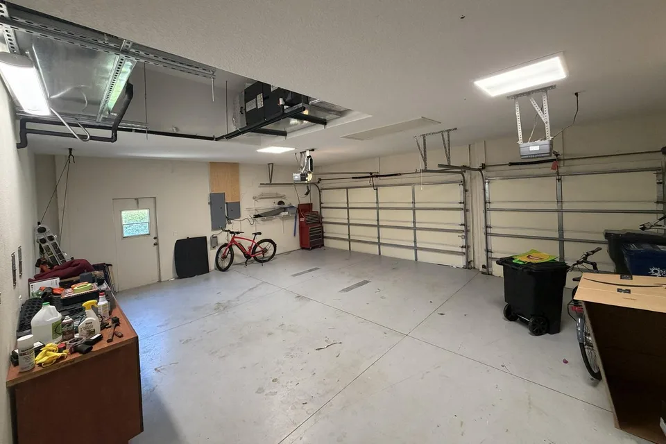 The garage before the work, with the original floor, wall-mounted racks, and belongings around the perimeter.